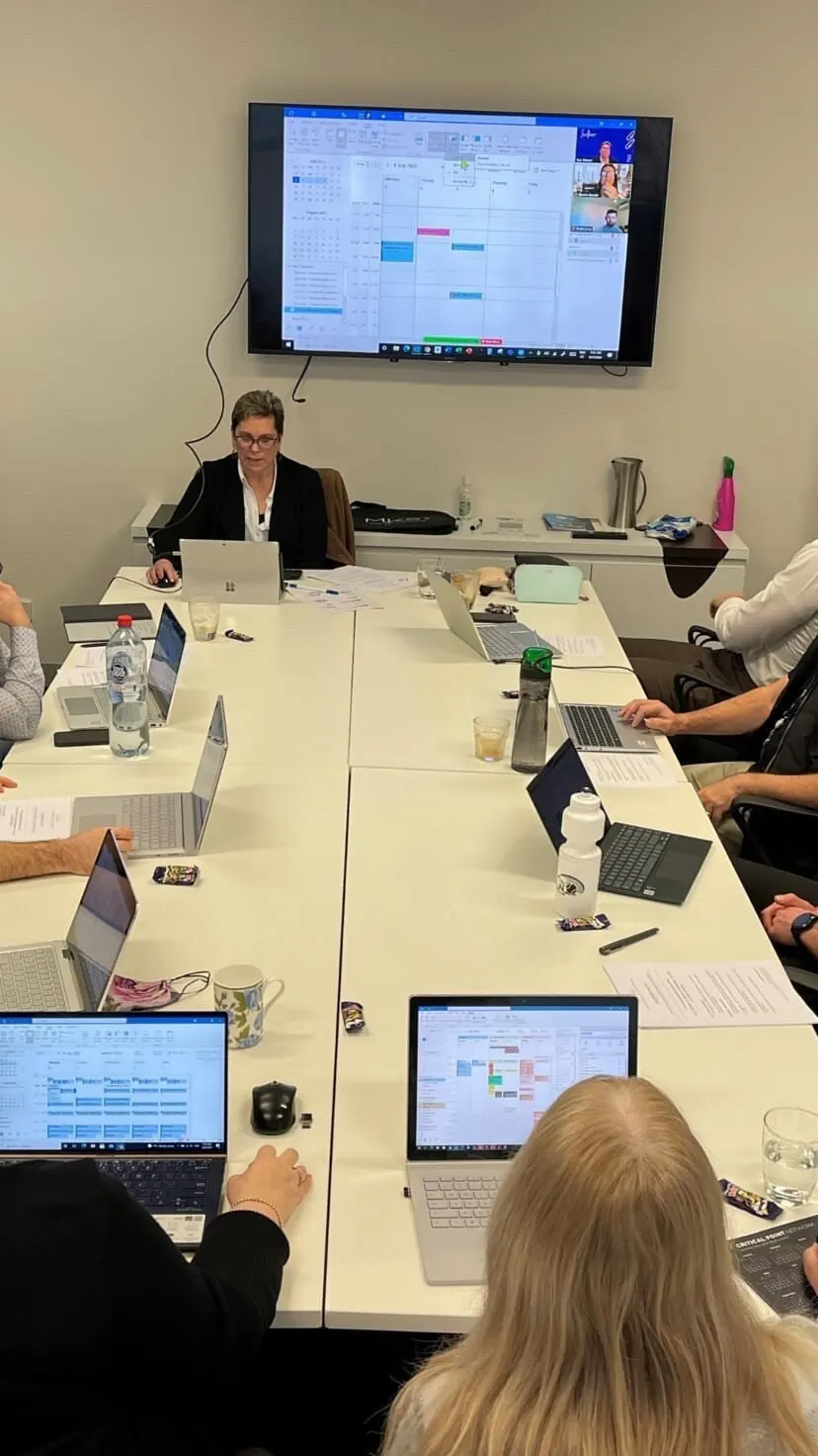 Sue running a calendar session for a team on laptops