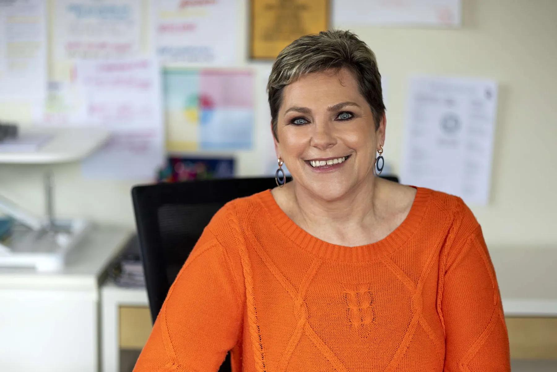 Sue Glasser smiling in her orange jumper