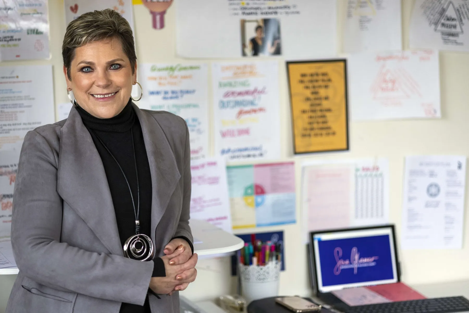 Sue in a grey blazer in front of goal-setting posters